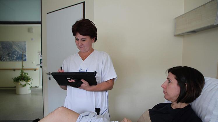 Mit dem Tablet am Bett: Krankenschwester Elena Eirich  "versorgt" Verwaltungsdirektorin Sabine Hein. Foto: Ulrike Müller