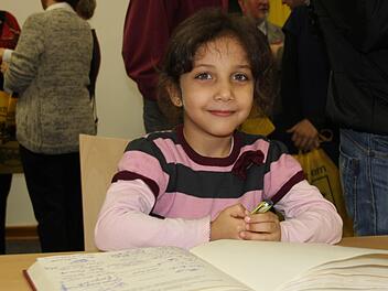 Die fünfjährige Aya Alachek aus Syrien studiert das Gästebuch der Stadt, in das sich alle Geehrten eingetragen haben.