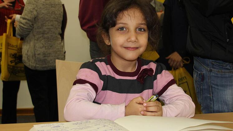 Die fünfjährige Aya Alachek aus Syrien studiert das Gästebuch der Stadt, in das sich alle Geehrten eingetragen haben.