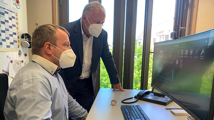 Jürgen Bischoff, Leiter Hauptverwaltung und IT im Landratsamt Bad Kissingen (Foto, vorne) zeigt Landrat Thomas Bold die Admin-Ansicht der Lüftungsgeräte, die auch von Bad Kissingen aus gesteuert werden können. Foto: Anja Vorndran/Landkreis Bad Kissingen