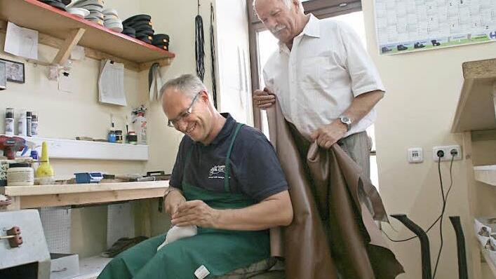 Heute schaut Vater Martin, der ein Kuhleder in der Hand hält, seinem Sohn Andreas bei der Arbeit über die Schulter.