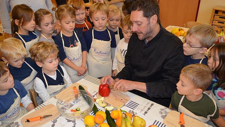 TV-Koch Mirko Reeh erklärt den Kindern, wie Obst und Gemüse zerkleinert werden. Foto: Gabi Bertram