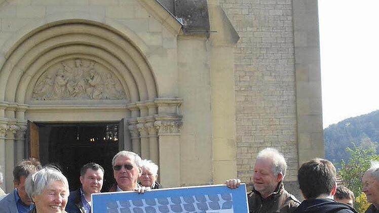 Kirchenpfleger Peter Koberstein und Edgar Reuter zeigen eine Foto- Collage der über 100 beschrifteten Dachschiefer, welche im sanierten Kirchendach eingebaut wurden. Foto: Markus Waite