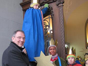Bürgermeister Thomas Nowak lässt sich den Segen von Caspar, Melchior und Balthasar an der Rathaustüre bestätigen. Rufus steht auf der Leiter, Jetta gleich daneben. Damit nichts passiert, hält Thomas Nowak die Leiter fest. Foto: Martin Koch