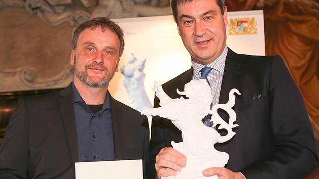 Markus S&ouml;der (rechts) &uuml;berreicht Volker Traumann, dem Vorsitzenden des Vereins Bamberger Kurzfilmtage, die Urkunde und den bayerischen L&ouml;wen. Foto: RiegerPress