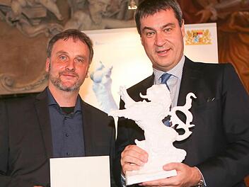 Markus S&ouml;der (rechts) &uuml;berreicht Volker Traumann, dem Vorsitzenden des Vereins Bamberger Kurzfilmtage, die Urkunde und den bayerischen L&ouml;wen. Foto: RiegerPress