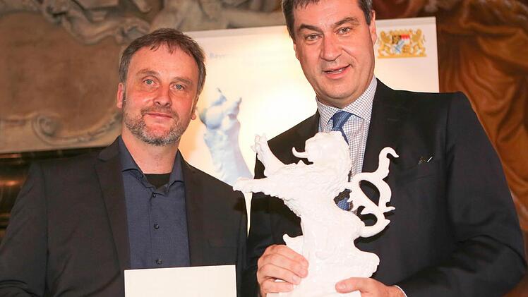 Markus S&ouml;der (rechts) &uuml;berreicht Volker Traumann, dem Vorsitzenden des Vereins Bamberger Kurzfilmtage, die Urkunde und den bayerischen L&ouml;wen. Foto: RiegerPress