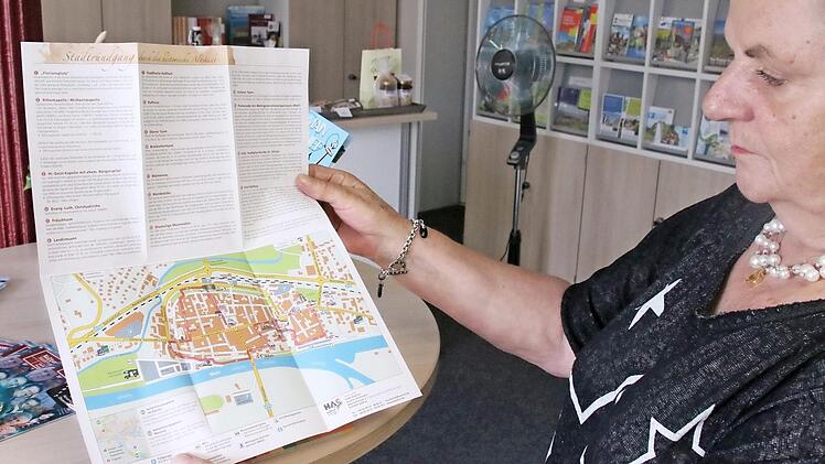 Eva-Maria Schwach von der Tourist-Info Haßfurt zeigt eine Faltmappe, mit der Besucher auf Stadtrundgang gehen können.