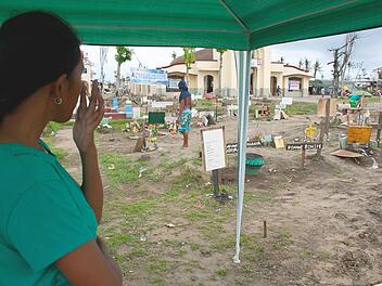 Die 22-jährige Michelle Maraya blickt vor der katholischen Kirche von San Joaquin auf den Philippinen auf Massengräber, in denen Opfer des Taifuns "Haiyan" beerdigt wurden. Foto: John Grafilo/dpa