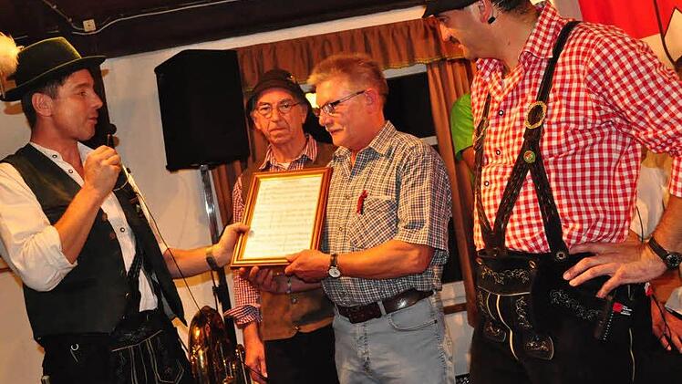 Jürgen Korn, der Vorsitzende des Musikvereins "Die Schlossberger" Hohnhausen überreicht an den Vorsitzenden des Heimatvereins "Die Schrollnhüpfer" Ibind, Johann Zellmann, die Partitur der Polka, fein sauber eingerahmt. Mit auf dem Bild Dieter Maisch (Mitte) und Uwe Rädlein von den Wirtshausschrollern.