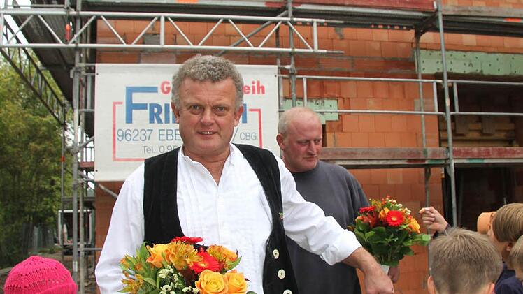 Zimmermann Gerhard Kögel ließ vom Dach des Gebäudes die Handwerkerschaft hochleben - und überreichte den Montessori-Verantwortlichen Blumensträuße.