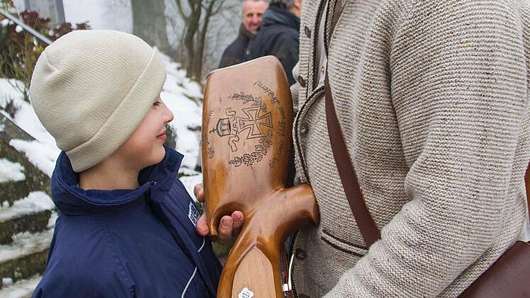 Der neunjährige Leo Bergmann aus Unfinden bewundert den Pranger Stützen, hergestellt in Berchtesgaden, vom Schützen Reinhold Schütz aus Ebensfeld: Er wiegt 13 Kilogramm. Fotos: Renè Ruprecht