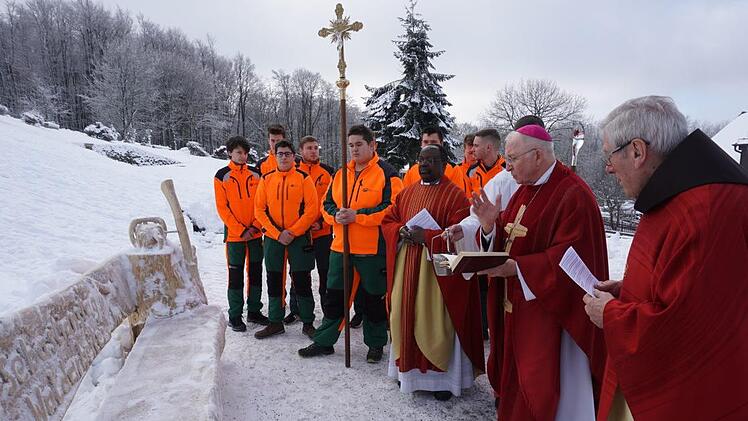 Anlässlich der Sebastiansmesse haben Marco Trabert, Robert Reuschler und Gotthard Schwender eine Bank auf dem Vorplatz zum Klosterkirche mit Motorsägenkunst erstellt. Das Bild zeigt die Auszubildenden der Bayerischen Staatsforstbetriebe Bad Bürckenau, Bad Königshofen und Heigenbrücken sowie Marco Trabert, Robert Reuschler, Gotthard Schwender, Dr. Ignace Matensi (Lohr), Weihbischof Ulrich Boom und Pater Martin Domogalla. Foto: Marion Eckert