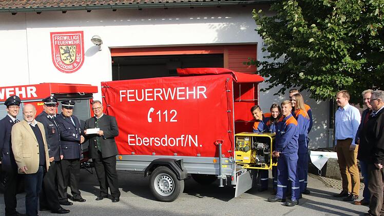 Kommandant Norbert Engel übergibt den Anhänger an den Dritten Bürgermeister der Stadt Neustadt, Martin Stingl. Währenddessen hebt  die Feuerwehrjugend aus Ebersdorf bei Neustadt schon einmal das Stromaggregat aus dem Anhänger. Foto: Michael Stelzner
