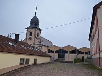 Die Gebäude an der Kirche stehen nah beieinander: Rechts ist die alte Schule zu sehen, links das ehemalige Lebensmittelgeschäft. Letzteres wird für den Umbau der Kirche weichen, ebenso wie der Anbau St. Pius in der Bildmitte. Auch der Schulhof wird verändert, denn die Mauer zur Kirche soll ebenfalls abgerissen werden. Foto: Kathrin Kupka-Hahn
