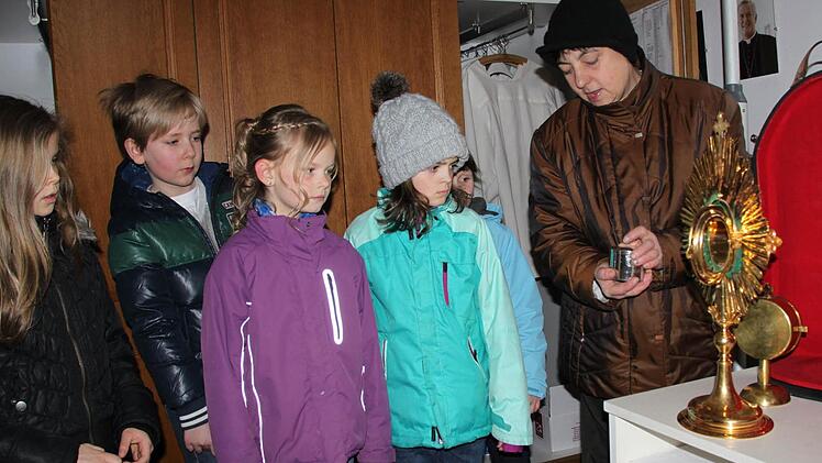 Mesnerin Marlena Müller zeigt den Kommunionkindern die goldene Monstranz, in die...