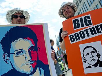 Edward Snowdens Enthüllungen nehmen ein immer größeres Ausmaß an. Hier halten Demonstranten in Hannover Plakate in die Kamera. Foto: Peter Steffen/dpa