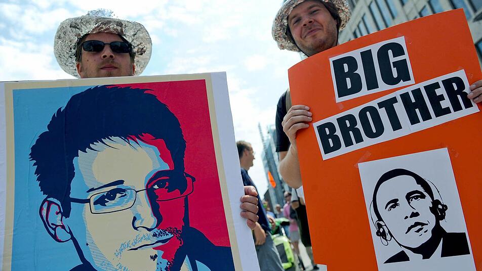 Edward Snowdens Enthüllungen nehmen ein immer größeres Ausmaß an. Hier halten Demonstranten in Hannover Plakate in die Kamera. Foto: Peter Steffen/dpa
