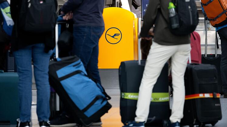 Passagiere warten an einem Check-In-Schalter der Lufthansa