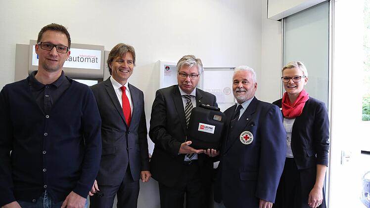 Bürgermeister Rüdiger Gerst (Mitte) bekommt von BRK-Kreisgeschäftsführer Klaus Otto den Defibrillator überreicht, der ab jetzt in der Sparkassenfiliale in Kemmern hängt. Auf dem Bild sind auch (von links) "Bamberg schockt"-Initiator Christoph Arend sowie Matthias Polz und Karina Müller von der Sparkasse zu sehen.  Foto: sem