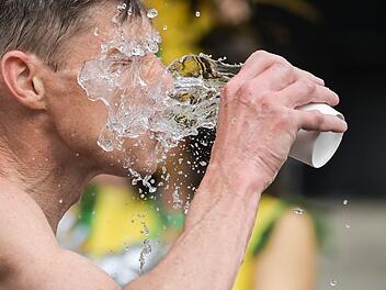 Ein Mann schüttet sich Wasser ins Gesicht