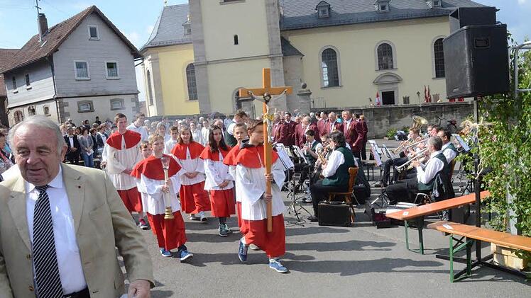 Ministranten und Geistliche beim Einzug zum festlich geschmückten Altarpodium. Im Hintergrund der Musikverein Glosberg und der Gesangverein "Liederkranz" Haig. Foto: Karl-Heinz Hofmann
