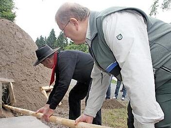 Olaf Schmidt (rechts) und Kurt Jakob entfachen den Kleintettauer Köhlermeiler. Foto: Veronioka Schadeck