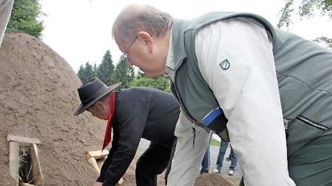 Olaf Schmidt (rechts) und Kurt Jakob entfachen den Kleintettauer Köhlermeiler. Foto: Veronioka Schadeck