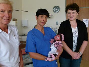 Die kleine Magdalena auf dem Arm von Kinderkrankenschwester Vicky Teller trägt Kleidung, die Veronika Schmitt (rechts) genäht hat.