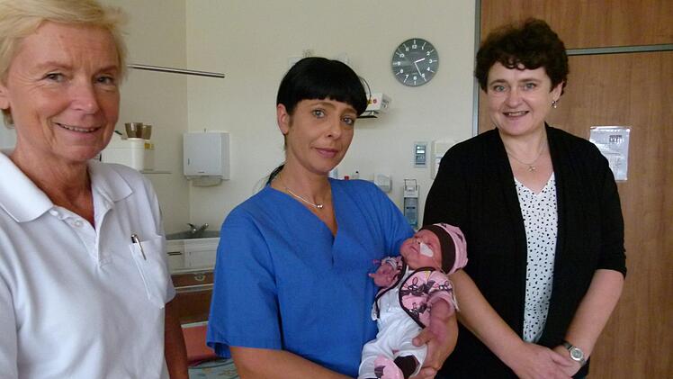 Die kleine Magdalena auf dem Arm von Kinderkrankenschwester Vicky Teller trägt Kleidung, die Veronika Schmitt (rechts) genäht hat.