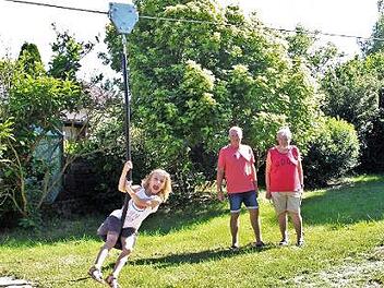 Mit der neuen Seilbahn über den Spielplatz zu sausen ist ein echtes Vergnügen für die fünfjährige Frida. Hans Czajka (r.) und Rainer Herdegen haben den Platz einst mit initiiert. Foto: Evi Seeger