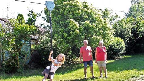 Mit der neuen Seilbahn über den Spielplatz zu sausen ist ein echtes Vergnügen für die fünfjährige Frida. Hans Czajka (r.) und Rainer Herdegen haben den Platz einst mit initiiert. Foto: Evi Seeger