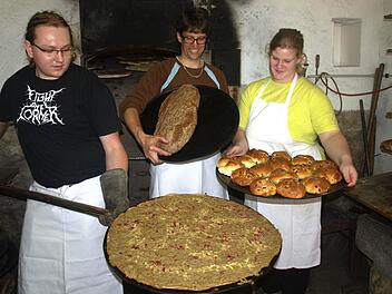 An der Ecke Hennebergstraße/Pfarrgasse richtete der Faschingsclub über zwei Tage sein Backhausfest aus. Vor allem die Köstlichkeiten aus dem Backofen lockten viele Besucher aus Ebenhausen und Umgebung. Andreas Ostermiller präsentiert hier einen Zwiebelplootz, Sascha Greubel ein Holzbackofenbrot und Lena Klüspies ein Blech mit Rosinenbrötchen. Foto: Stefan Geiger