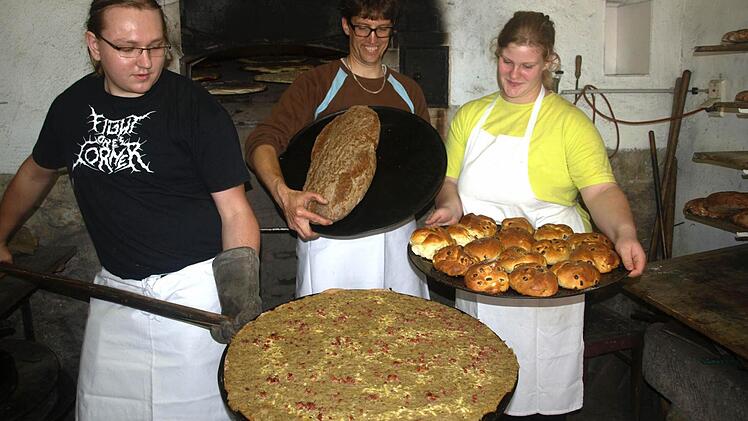 An der Ecke Hennebergstraße/Pfarrgasse richtete der Faschingsclub über zwei Tage sein Backhausfest aus. Vor allem die Köstlichkeiten aus dem Backofen lockten viele Besucher aus Ebenhausen und Umgebung. Andreas Ostermiller präsentiert hier einen Zwiebelplootz, Sascha Greubel ein Holzbackofenbrot und Lena Klüspies ein Blech mit Rosinenbrötchen. Foto: Stefan Geiger