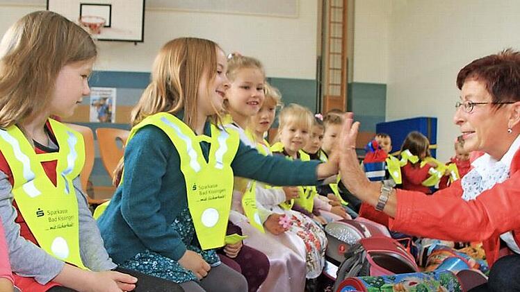 Roswitha Kaufmann von der Saale-Zeitung verteilte die Sicherheitsdreiecke an die Schulanfänger. Mit Handschlag versprachen ihr Mädchen, die Dreiecke auch zuverlässig zu tragen. Foto: Heike Beudert