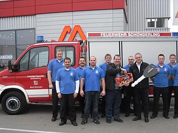 Stolz auf ihr neues Fahrzeug ist die Schönderlinger Feuerwehr, in der Mitte Bürgermeister Bernold Martin, mit einem kleinen Modell, und Kommandant Marko Knüttel, mit dem großen Schlüssel. Foto: Oswald Türbl