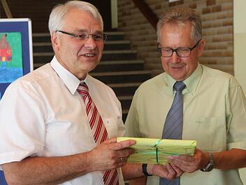 Schulamtsdirektor Wolfgang Blos (l.) überreicht dem scheidenden Schulleiter Günter Hoch ein Buch als Geschenk. Fotos: Franz Galster