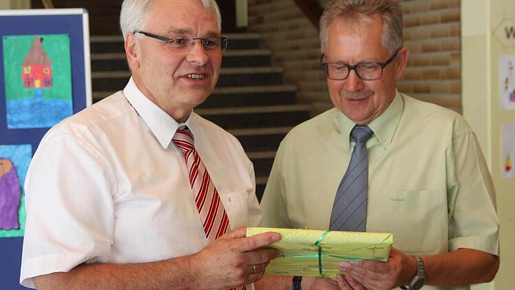 Schulamtsdirektor Wolfgang Blos (l.) überreicht dem scheidenden Schulleiter Günter Hoch ein Buch als Geschenk. Fotos: Franz Galster