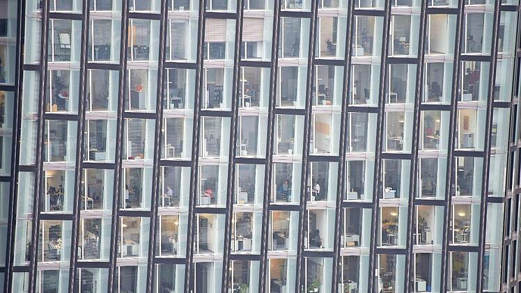 Menschen sitzen in Hamburg in einem Bürogebäude.  Foto: Lukas Schulze, dpa