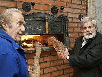 Gottfried Schneid (links) feuert den Backofen zusammen mit Bürgermeister Konrad Weingart zum ersten Mal an. Fotos: Arkadius Guzy