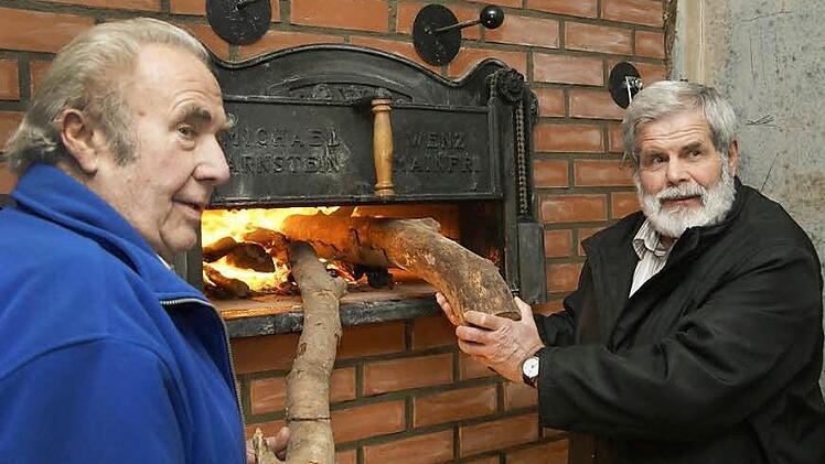 Gottfried Schneid (links) feuert den Backofen zusammen mit Bürgermeister Konrad Weingart zum ersten Mal an. Fotos: Arkadius Guzy