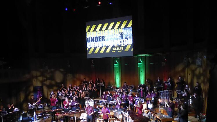 Ganz schön eng wurde es auf der Bühne im Max-Littmann-Saal bei Thomas Friedrichs Großveranstaltung in der "7. Nacht der Percussion": Hinten links der Hausener Chor Chorisma mit seiner Leiterin Antje Kopp, hinten rechts die Bläserband, vorne rechts das Cello von Claudia Dunkelberg, vorne links E-Gitarrist und Keyboarderin, im Zentrum Kisspercussiva, deren Leiter Thomas Friedrich von rechts begeistert applaudiert. Gerhild Ahnert