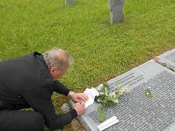 Heinrich Bätz unterschreibt auf der Grabliegeplatte den Brief, den er für seinen Vater verfasst hat.  Fotos: Monika Kukowski