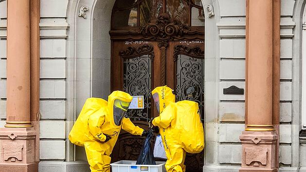 Einsatzkr&auml;fte in Chemikalienschutzanz&uuml;gen nehmen  eine erste Untersuchung der T&uuml;te vor.