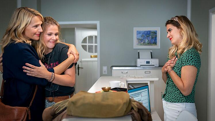 Nora Kaminski (Tanja Wedhorn, links) schließt ihr Schwesterherz Franziska (Tina Amon Amonsen) in die Arme. Sprechstundenhilfe Mandy (Morgane Ferru, rechts) freut sich über den überraschenden Besuch.