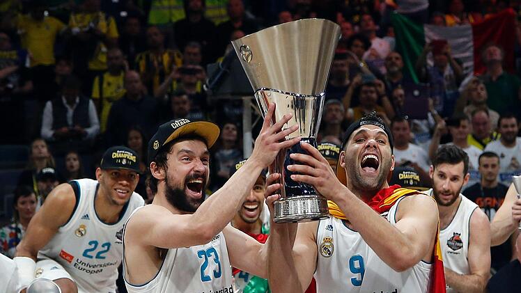 Felipe Reyes (vorne rechts) und Sergio Llull (vorne links) von Real Madrid zeigen den gewonnenen Pokal mit ihrer Mannschaft (hinten). Foto: Darko Vojinovic/dpa