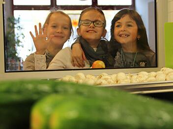 Drei Schülerinnen werfen einen Blick in die Küche der Sinnbergschule. Dort warten frische Gurken und Pilze darauf, zum Mittagessen für 85 Kinder weiterverarbeitet zu werden.  Fotos: Benedikt Borst