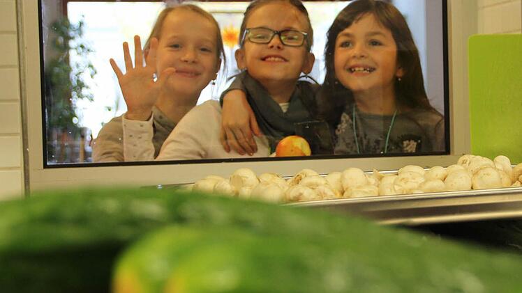 Drei Schülerinnen werfen einen Blick in die Küche der Sinnbergschule. Dort warten frische Gurken und Pilze darauf, zum Mittagessen für 85 Kinder weiterverarbeitet zu werden.  Fotos: Benedikt Borst