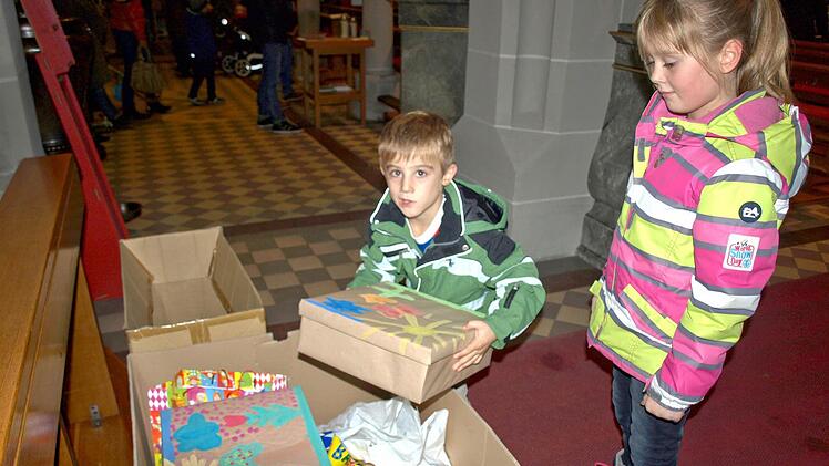 Auch Niklas (li.) und Julia Ebert legen ihre Geschenke für bedürftige Flüchtlingskinder in die Spendenschachtel.  Foto: Susanne Deuerling