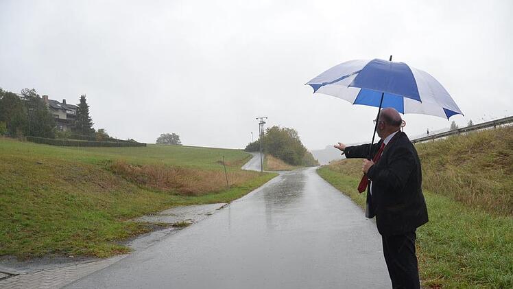 Letztlich wurde Bürgermeister Egon Herrmann nicht im Regen stehen gelassen wie es das Bild am Baugebiet Sachspfeife ausdrücken könnte. Hinter der Straße im Hintergrund soll das Baugebiet entstehen, für das noch eine Studie zur Feuersicherheit abgewartet werden muss. K.-H. Hofmann